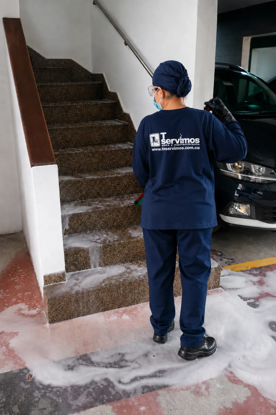 Operaria de Te Servimos lavando las escaleras de acceso a un parqueadero