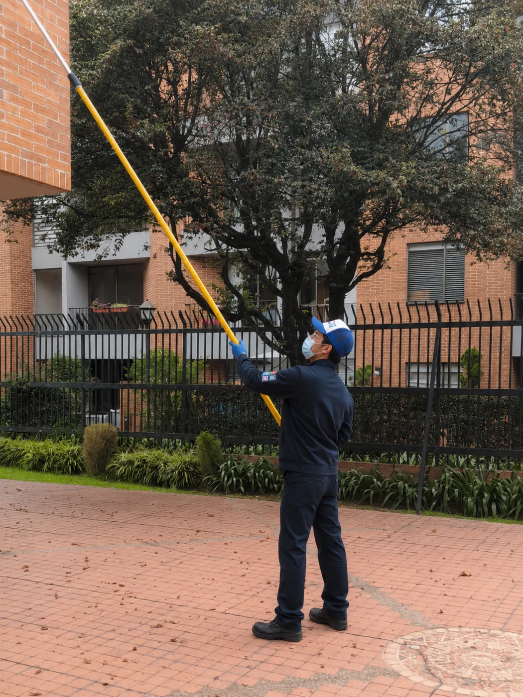 Operario de Te Servimos limpiando en altura con pértiga telescópica en la fachada de un conjunto