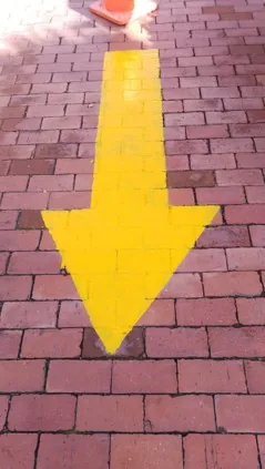 Después — La misma flecha repintada en amarillo, con los bordes definidos