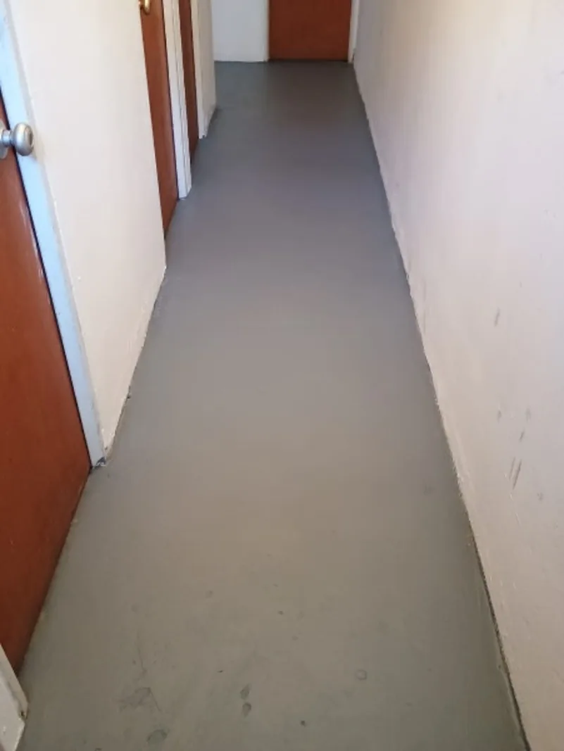 Después — El mismo corredor con el piso sellado y pintado en gris uniforme